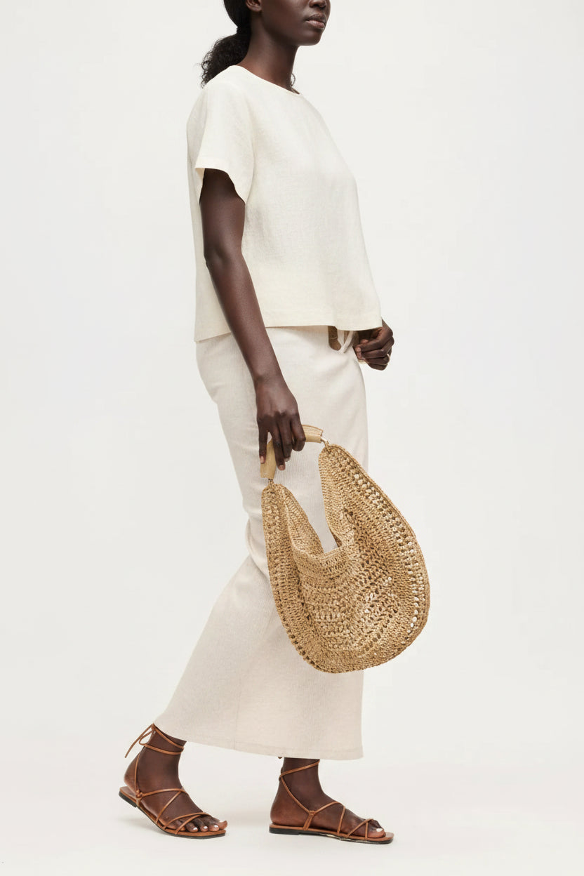 Person holding a woven straw bag with a plain background