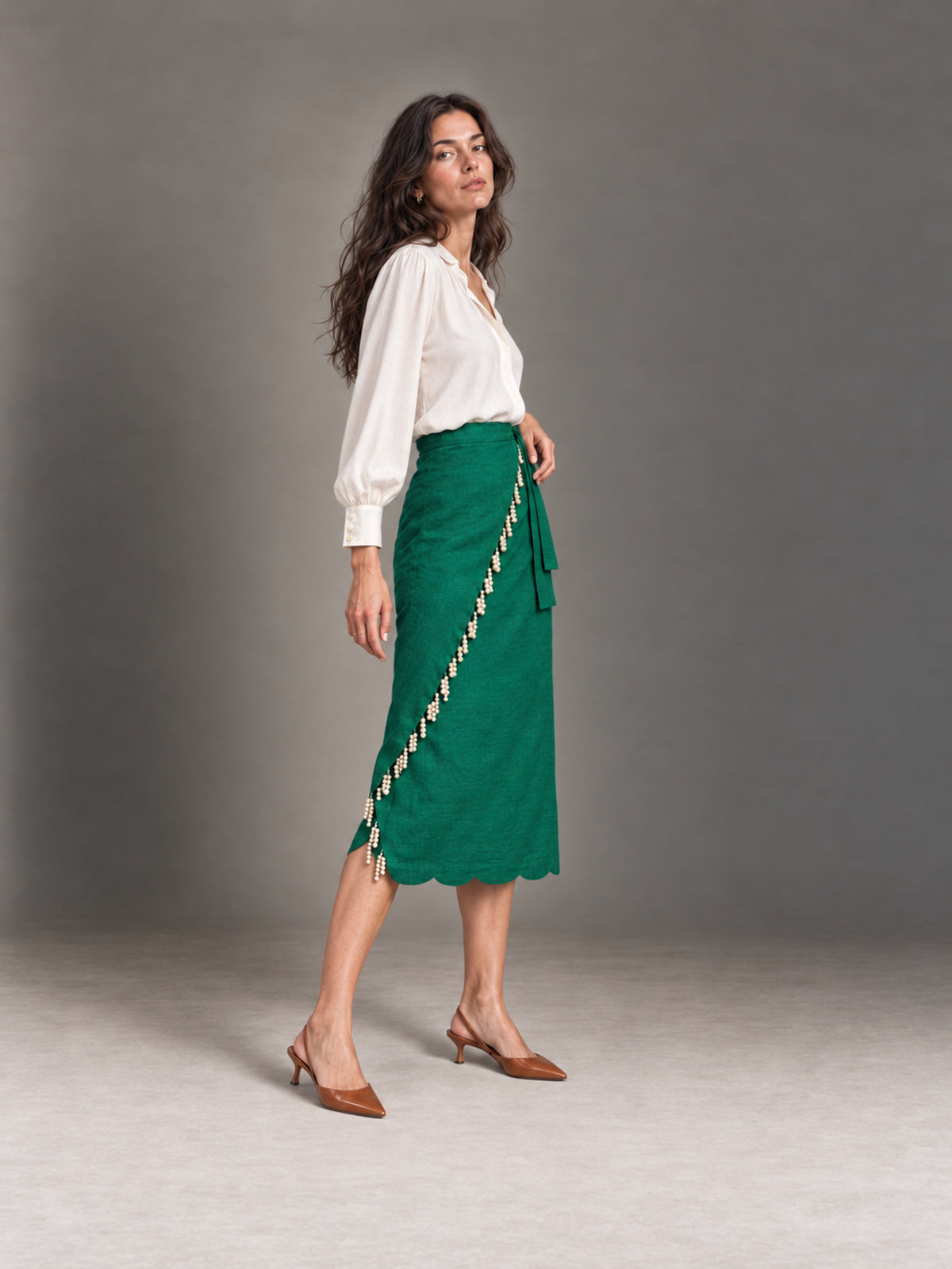 Ava wearing the green pearled wrap skirt in an elegant side pose