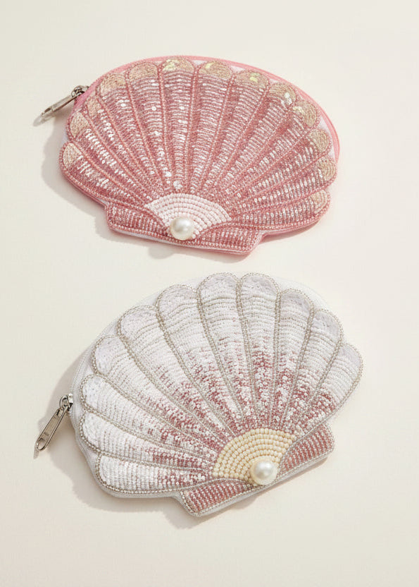 Three shell-shaped pouches in pink, white, and green on a light beige background
