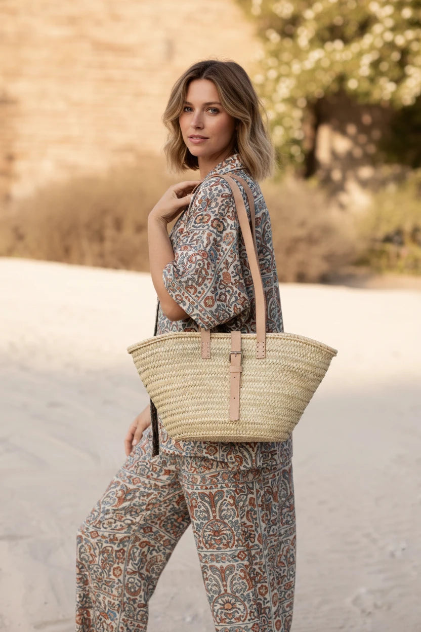 Woman in a yellow dress holding a straw bag on a sandy background