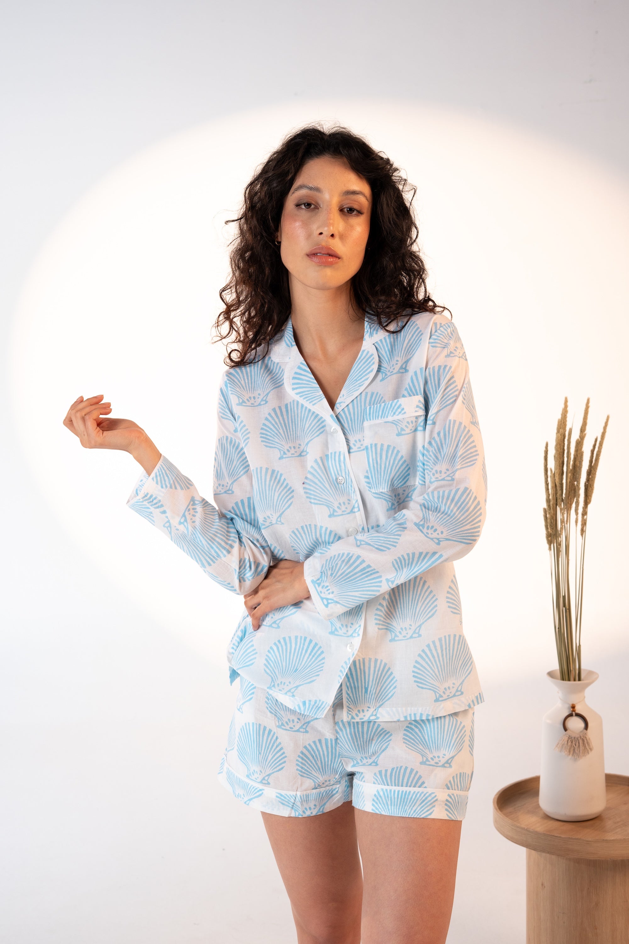Woman wearing a light blue and white patterned pajama set on a white background