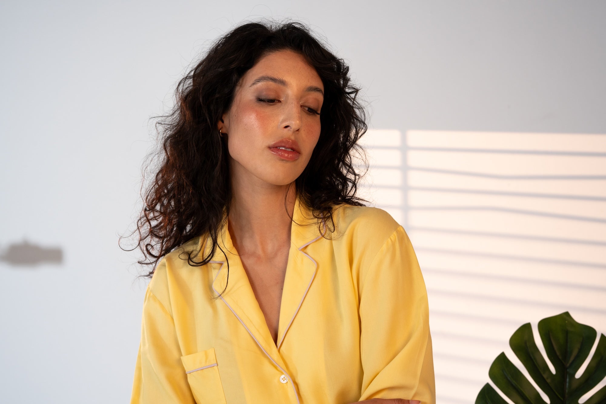 Woman wearing a yellow pajama top with a neutral background