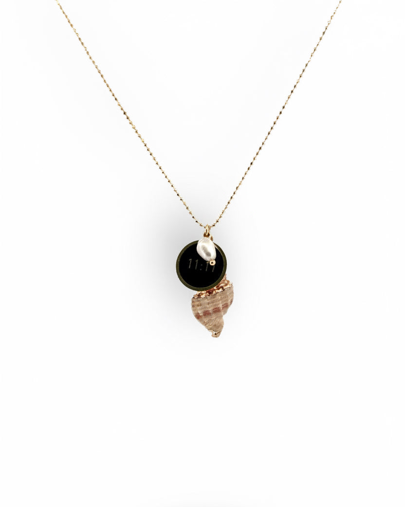A gold necklace with a natural seashell pendant painted with gold, a freshwater pearl, and a gold coin metal charm.