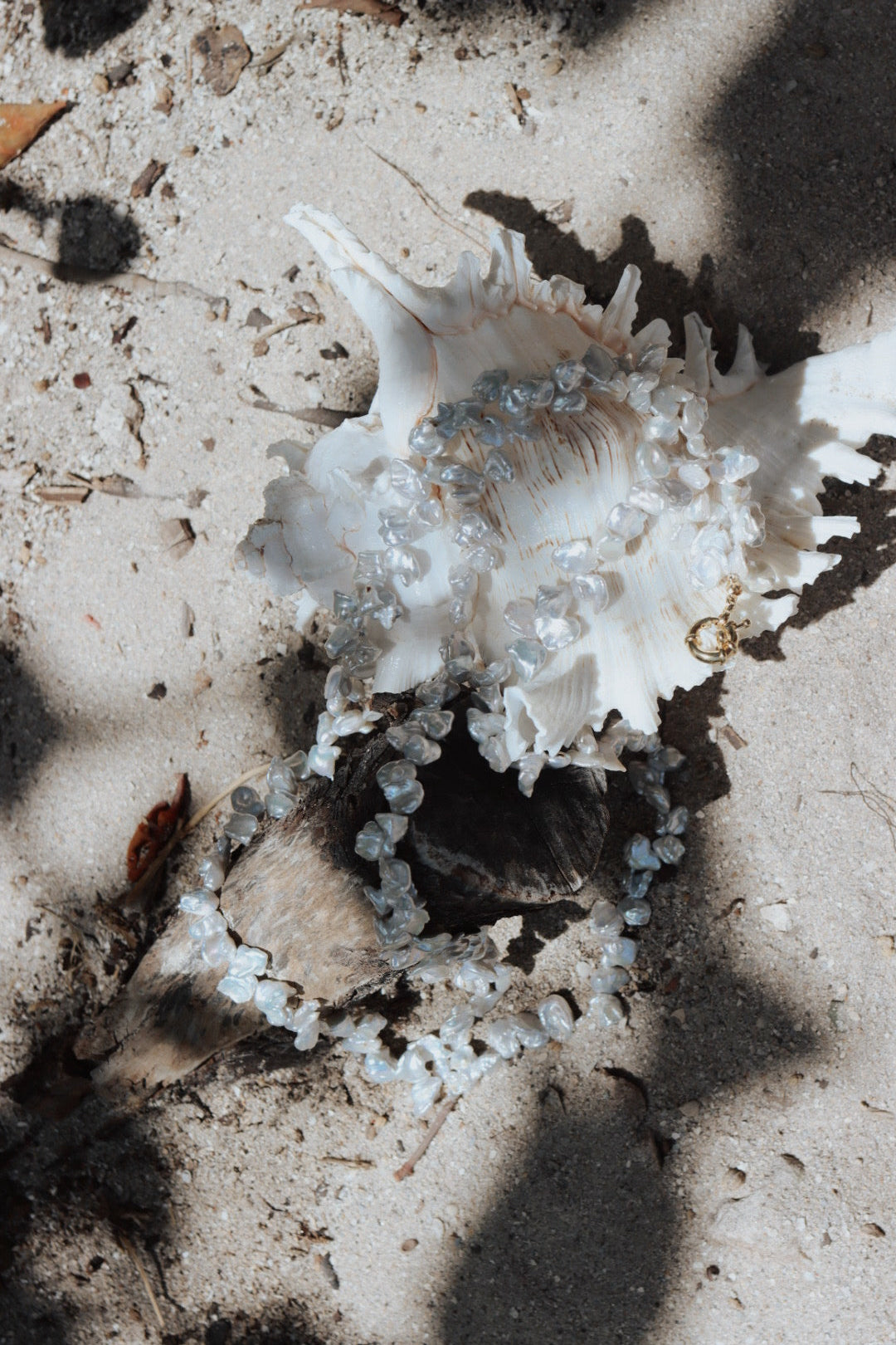 Baroque Garden Necklace styled on a white seashell and driftwood, photographed on sand with natural light highlighting the pearl texture