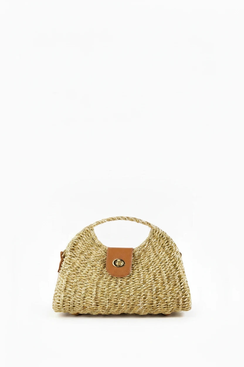 Woven straw handbag with a brown leather patch on a wooden surface