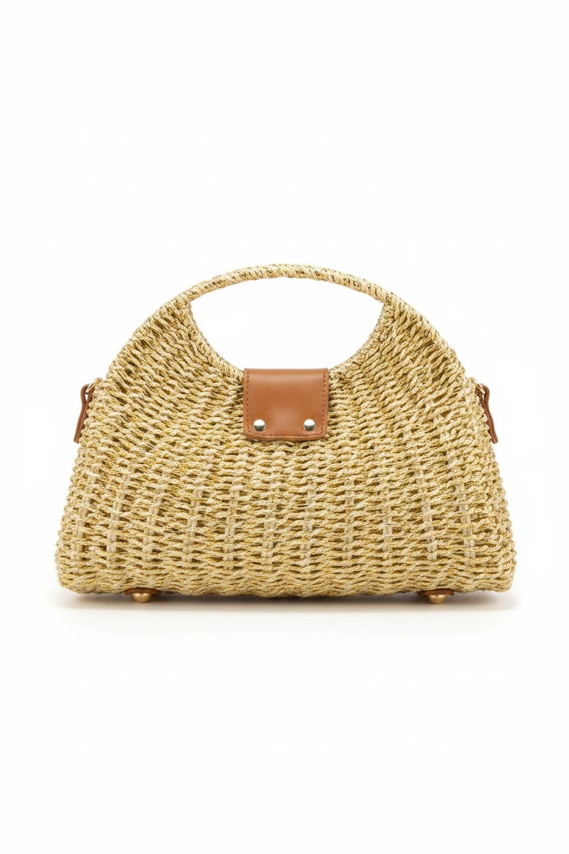 Woven straw handbag with brown leather accents on a wooden surface