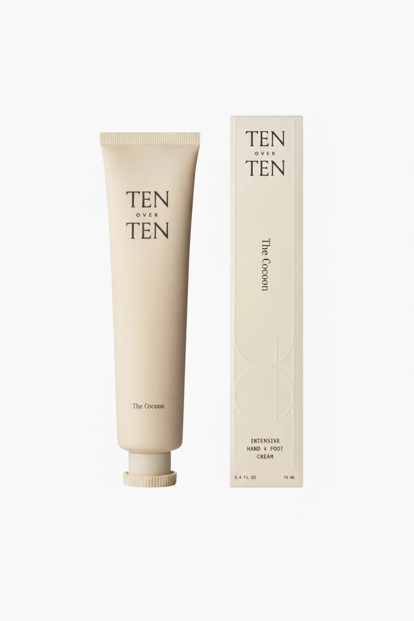 A beige tube of Ten Over Ten The Cocoon hand cream next to its packaging box.