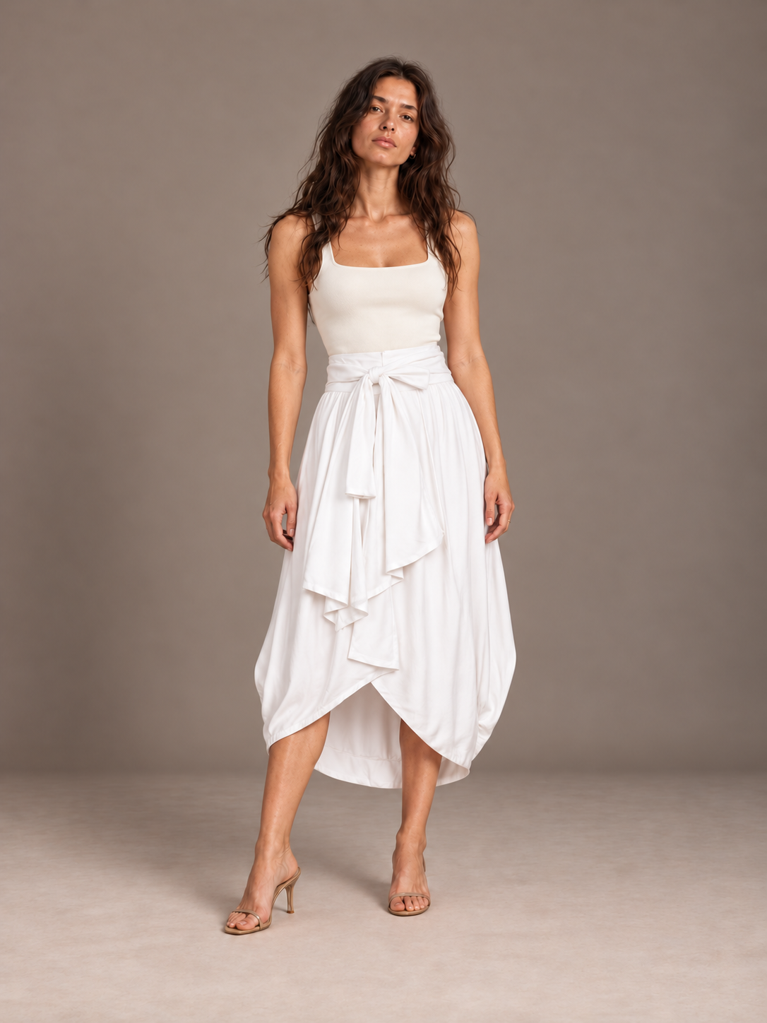 Front view of the white Cocoon Bamboo Bow Skirt with a wide waist bow, styled with an ivory square-neck top in a gray studio