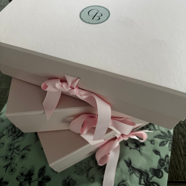 White gift box with pink ribbon on a floral-patterned surface