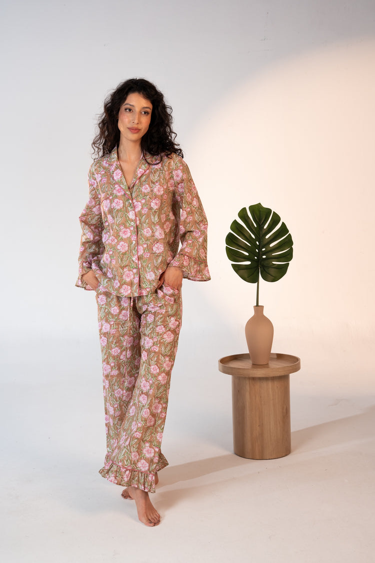 Woman wearing a floral pajama set standing next to a small table with a plant on it.