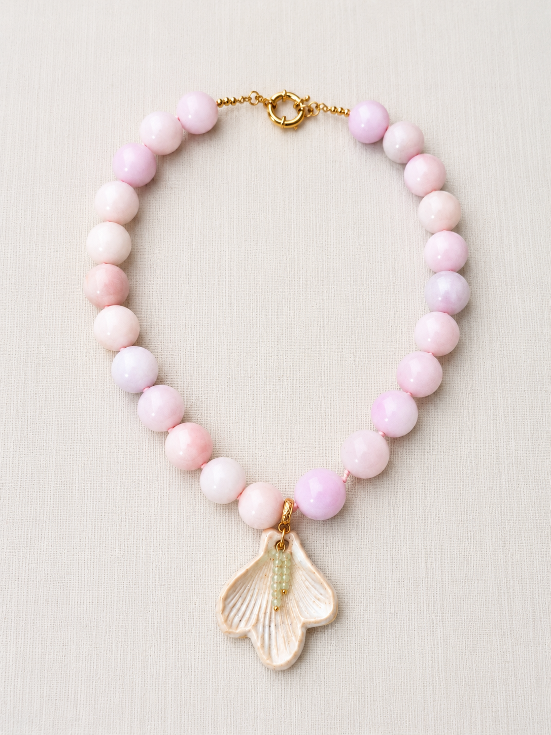 Necklace with pink beads and a shell pendant on a light background