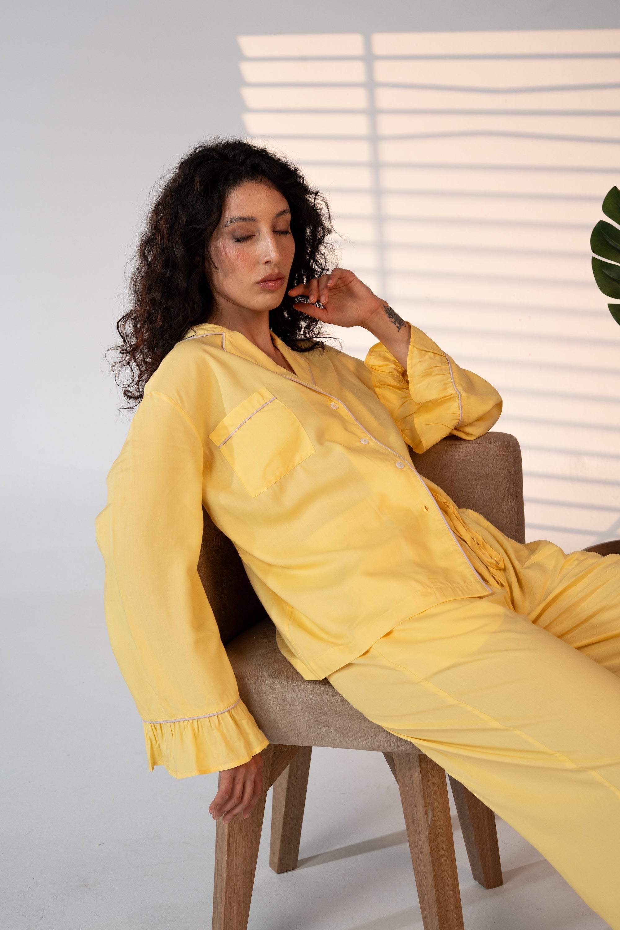 Woman in a yellow outfit sitting on a chair with a neutral background