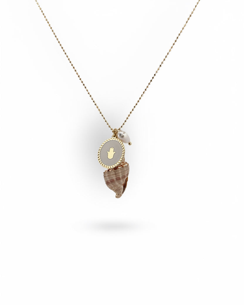 A gold necklace with a natural seashell pendant painted with gold, a freshwater pearl, and a gold coin metal charm.