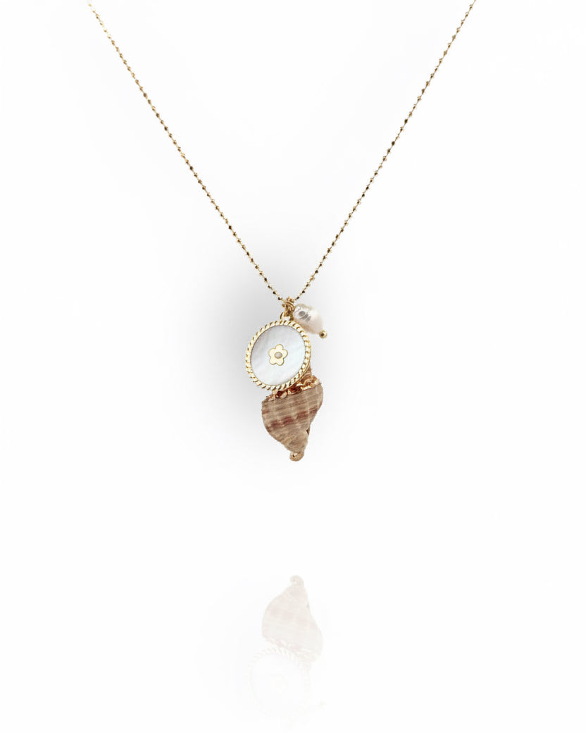 A gold necklace with a natural seashell pendant painted with gold, a freshwater pearl, and a gold coin metal charm.