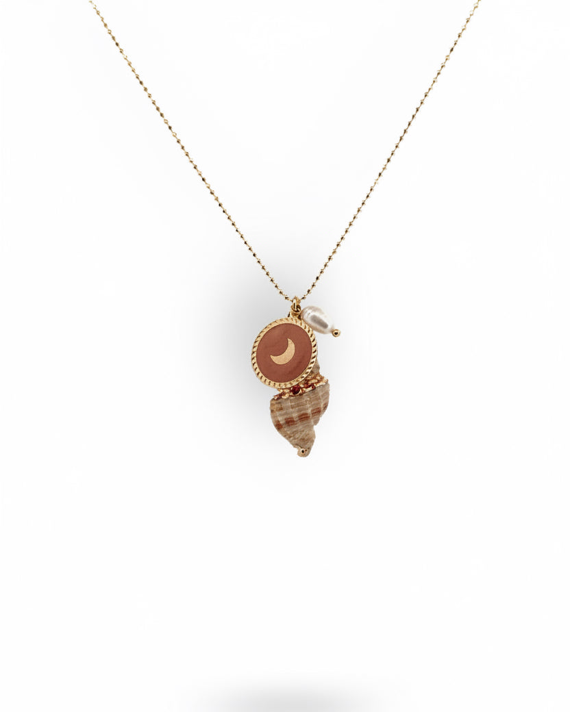 A gold necklace with a natural seashell pendant painted with gold, a freshwater pearl, and a gold coin metal charm.