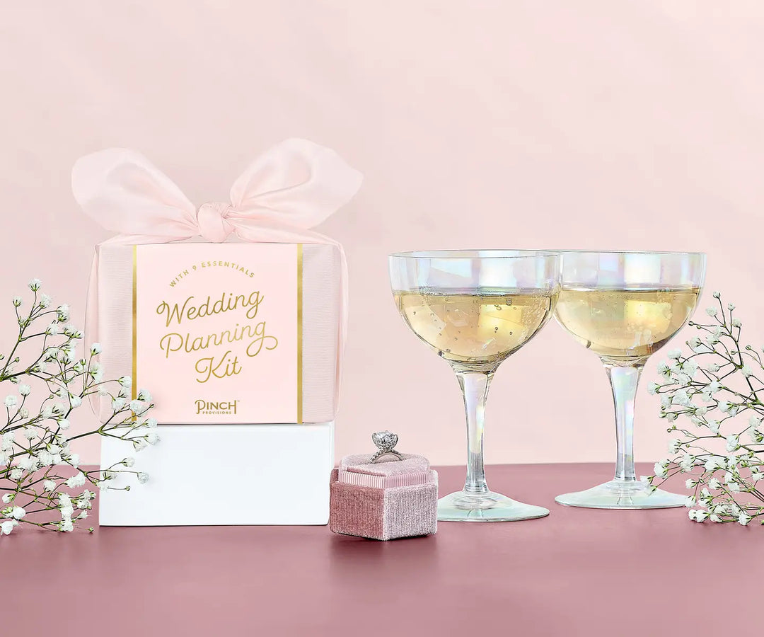 Wedding planning kit with glasses of champagne on a pink background