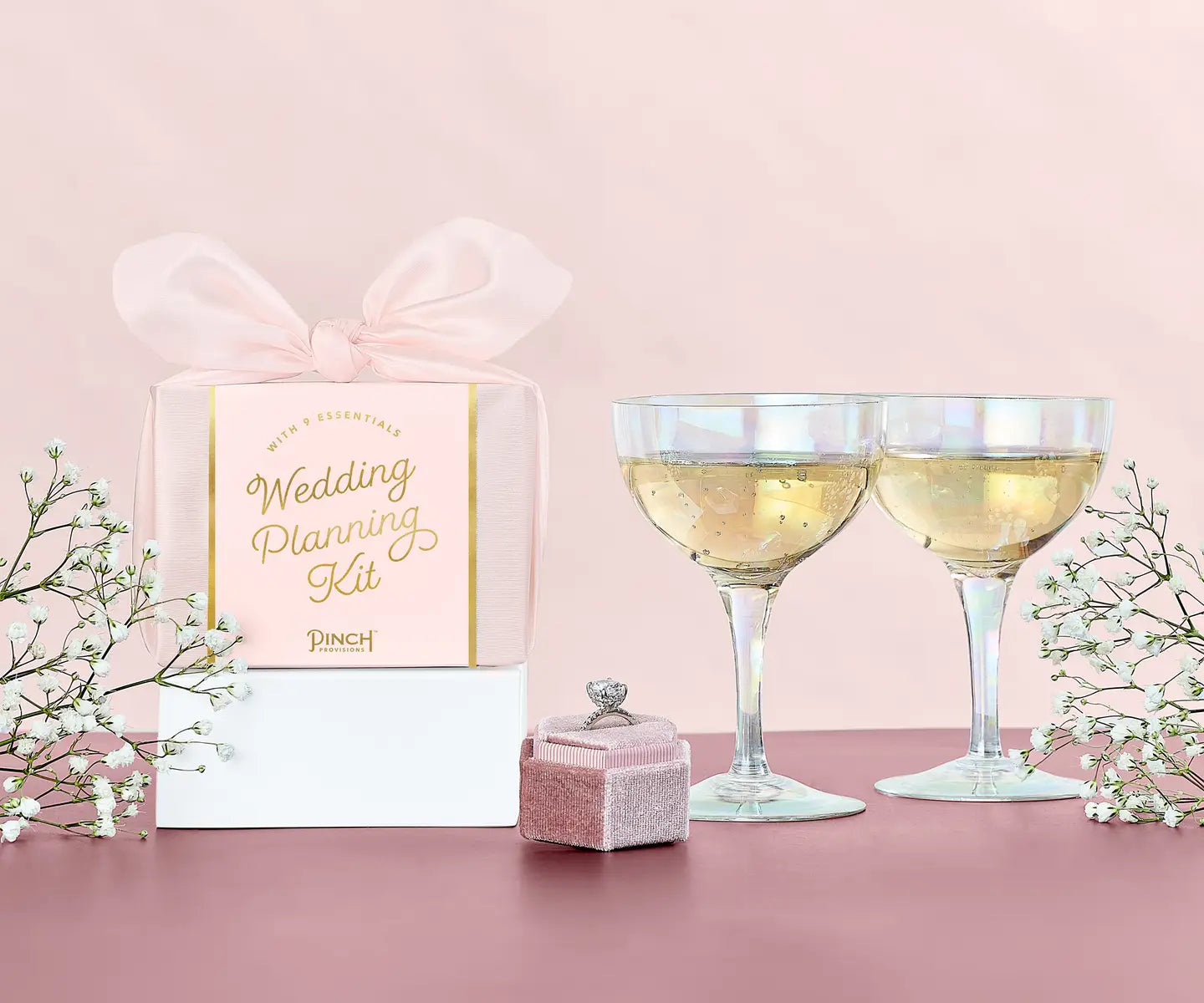 Wedding planning kit with glasses of champagne on a pink background