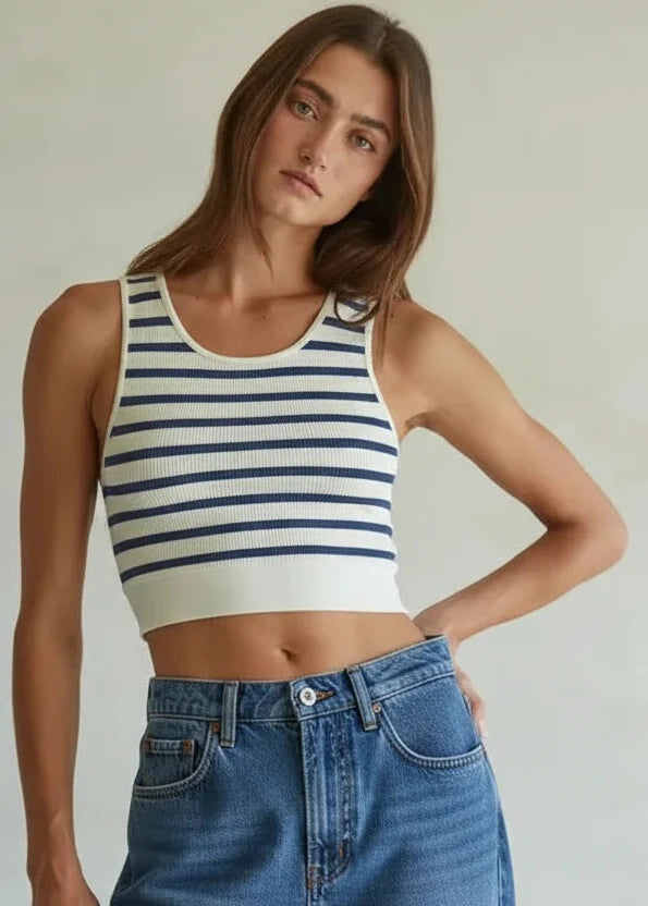 Woman wearing a striped tank top and blue jeans against a plain background