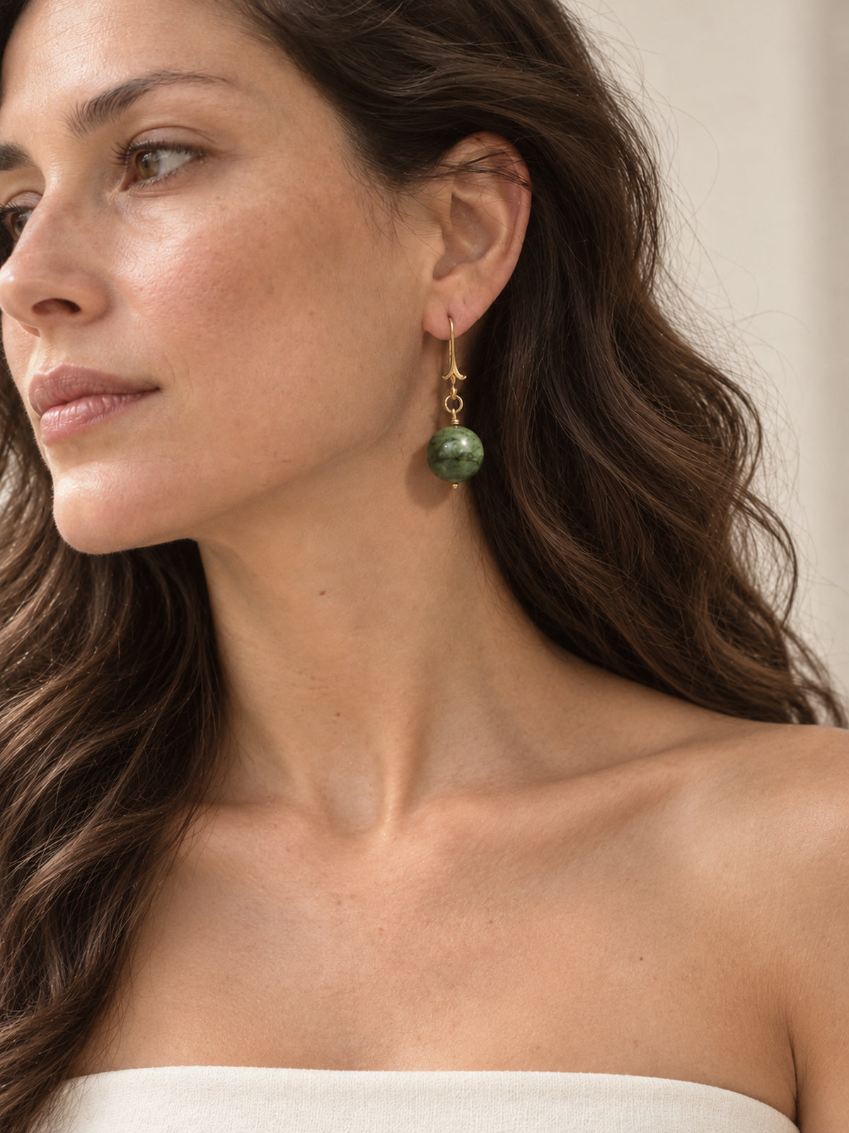 Model wearing green jasper drop earrings and an ivory strapless top