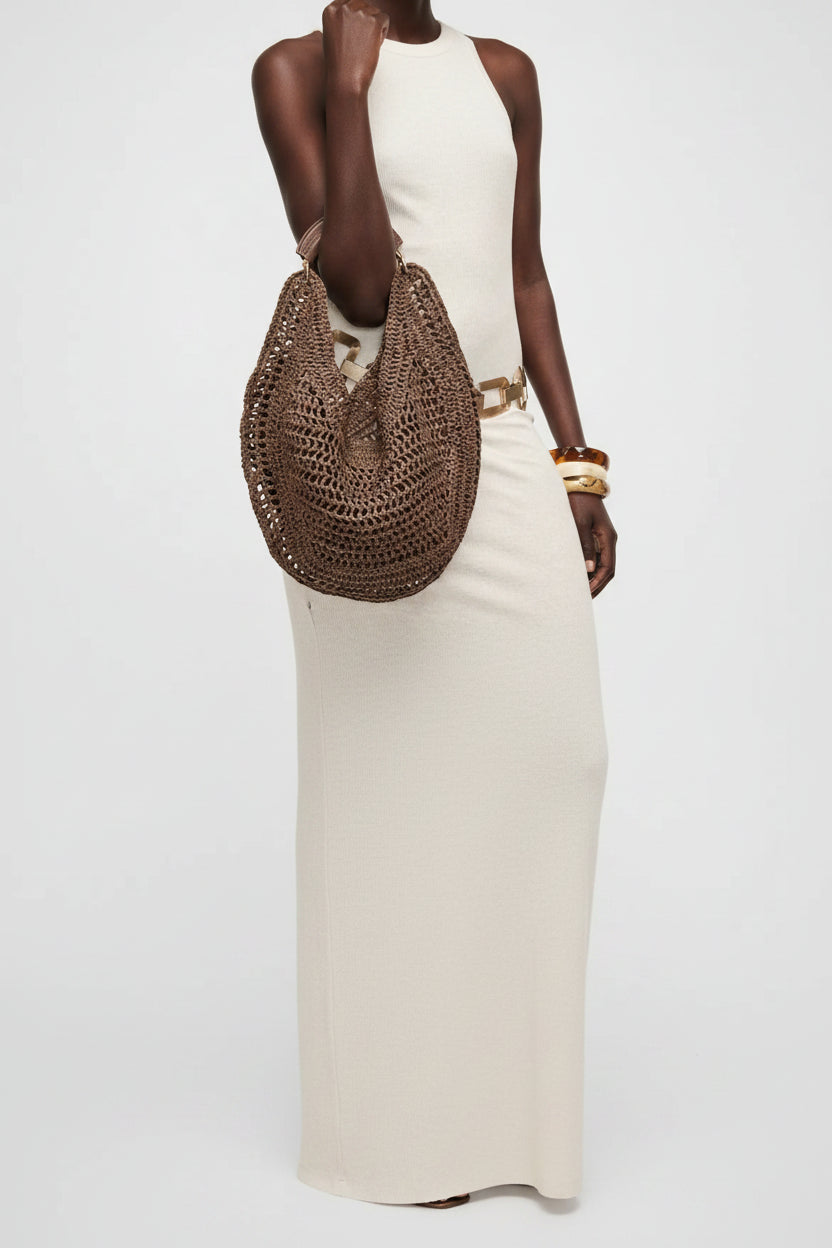 Brown woven handbag held by a person on a light gray background