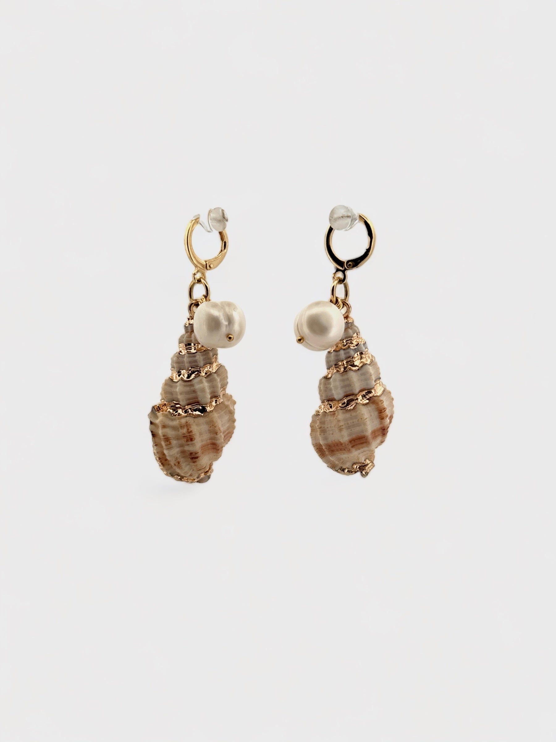 Close-up of gold-painted shell earrings with dangling freshwater pearls, displayed on a neutral background.