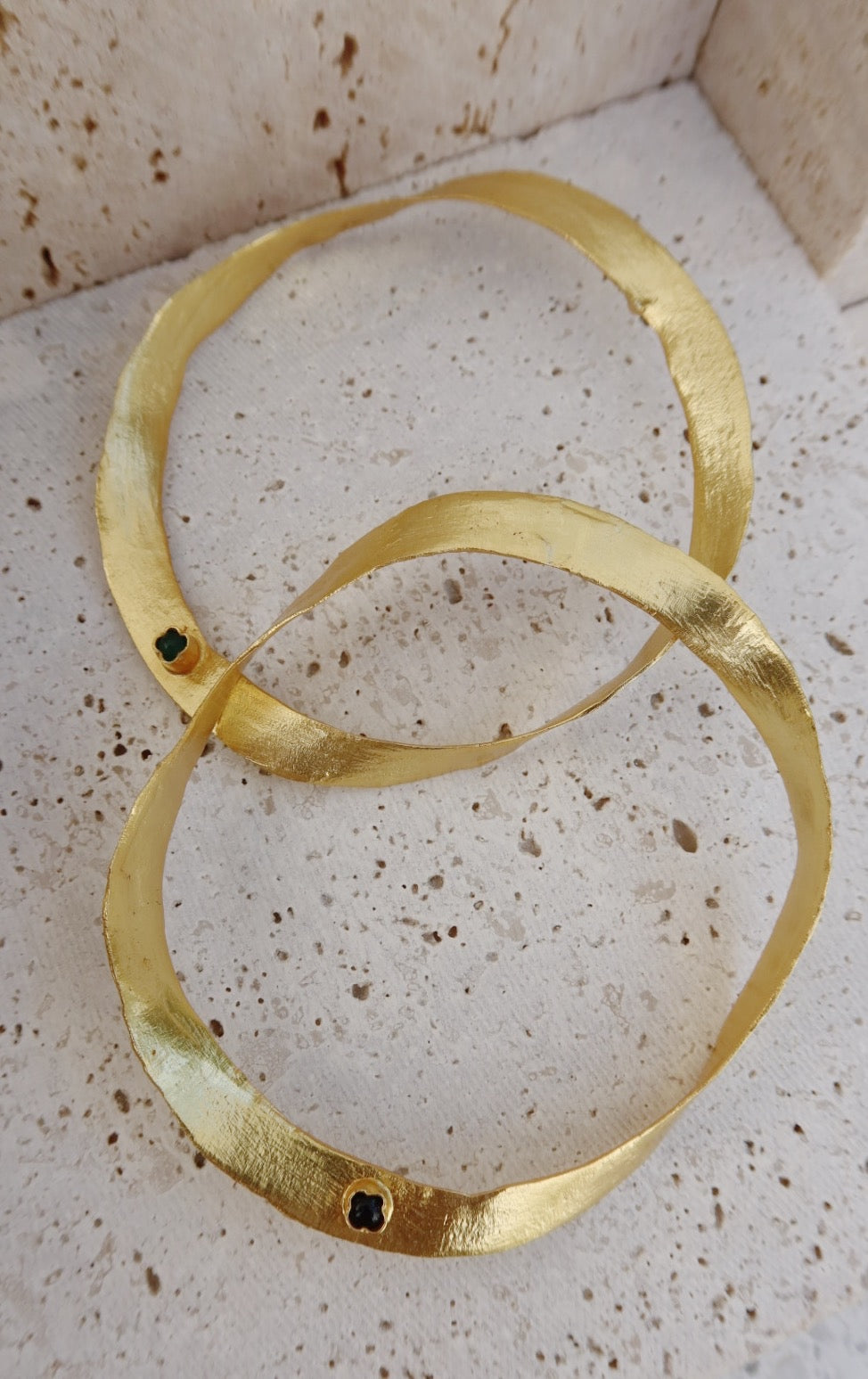 Close-up of Bangled Paper Ribbon Bracelet showing irregular gold texture and round black onyx stone detail