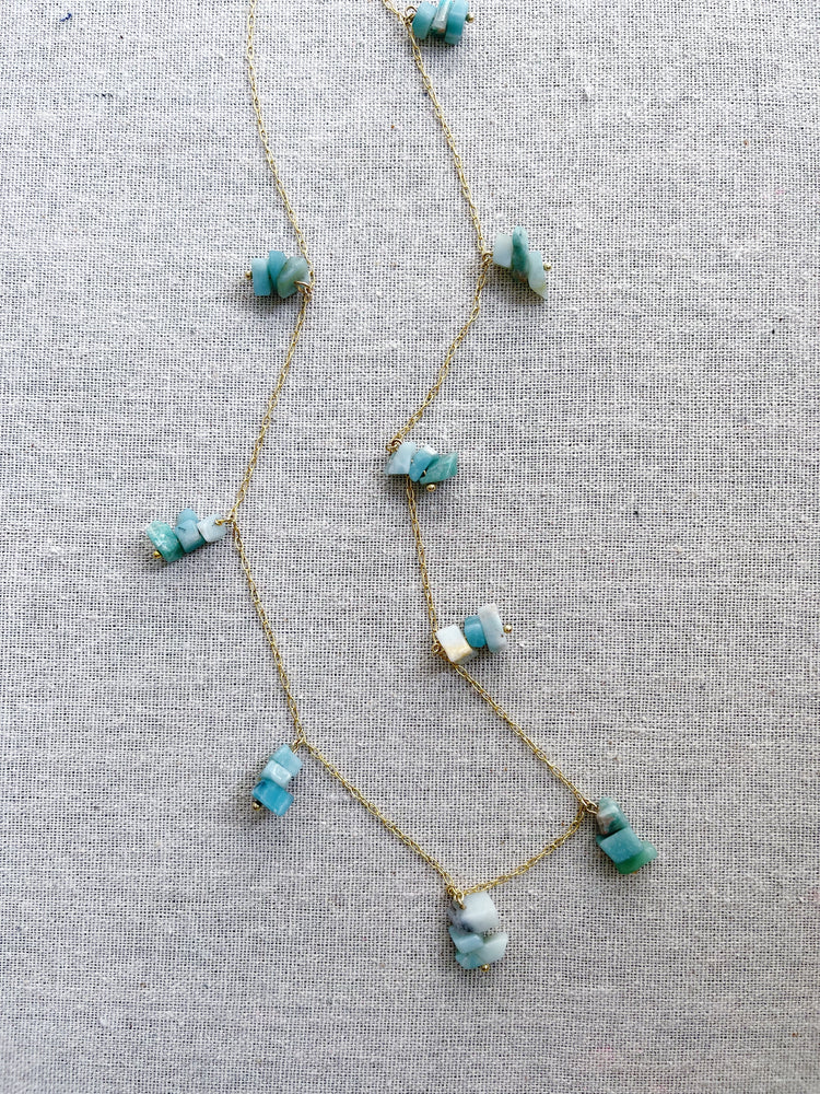 A gold necklace featuring groups of aquamarine stones.   The aquamarine stone is used in holistic healing and crystal therapy.  Spiritually, aquamarine is associated with trusting and letting go. In ancient times, aquamarine was believed to be the treasure of mermaids. Sailors used the stone as a talisman to bring good luck on the open waters. The gem was used as a symbol of protection and fearlessness too.  Aquamarine  14k plated gold chain  30” long