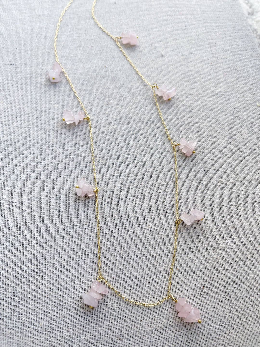 A gold necklace featuring groups of pink quartz stones.   The pink quartz stone is used in holistic healing and crystal therapy.  Rose quartz is known as a healing crystal and the stone of unconditional love. It's believed by some to emit strong vibrations of love, which are thought to: support emotional and relationship healing. inspire compassion.  Pink quartz  14k plated gold chain