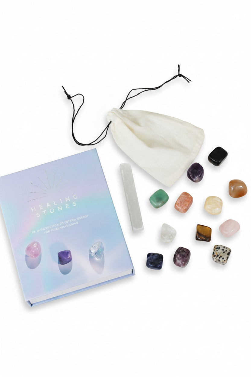 Collection of healing stones, a bag, and a book on a marble surface.
